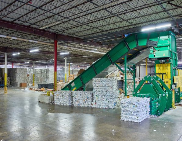 a warehouse with a conveyor belt carrying stacks of cardboard