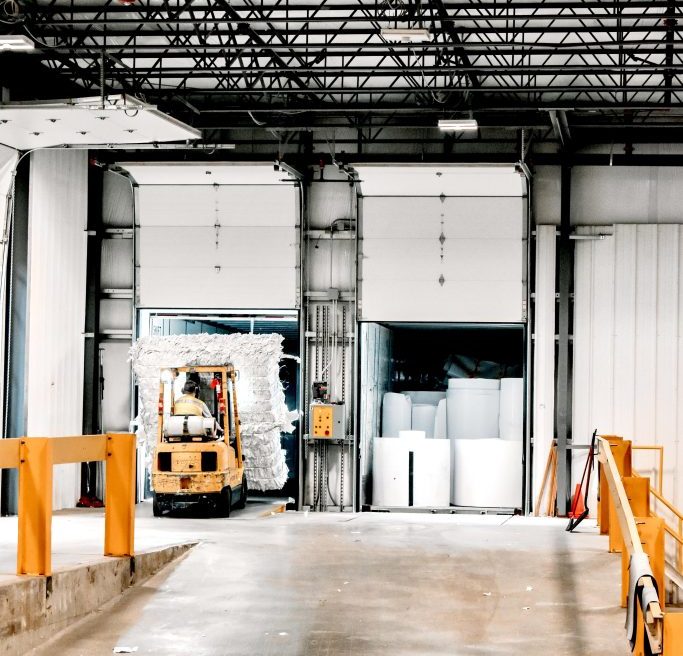 a yellow forklift is carrying a large load of paper